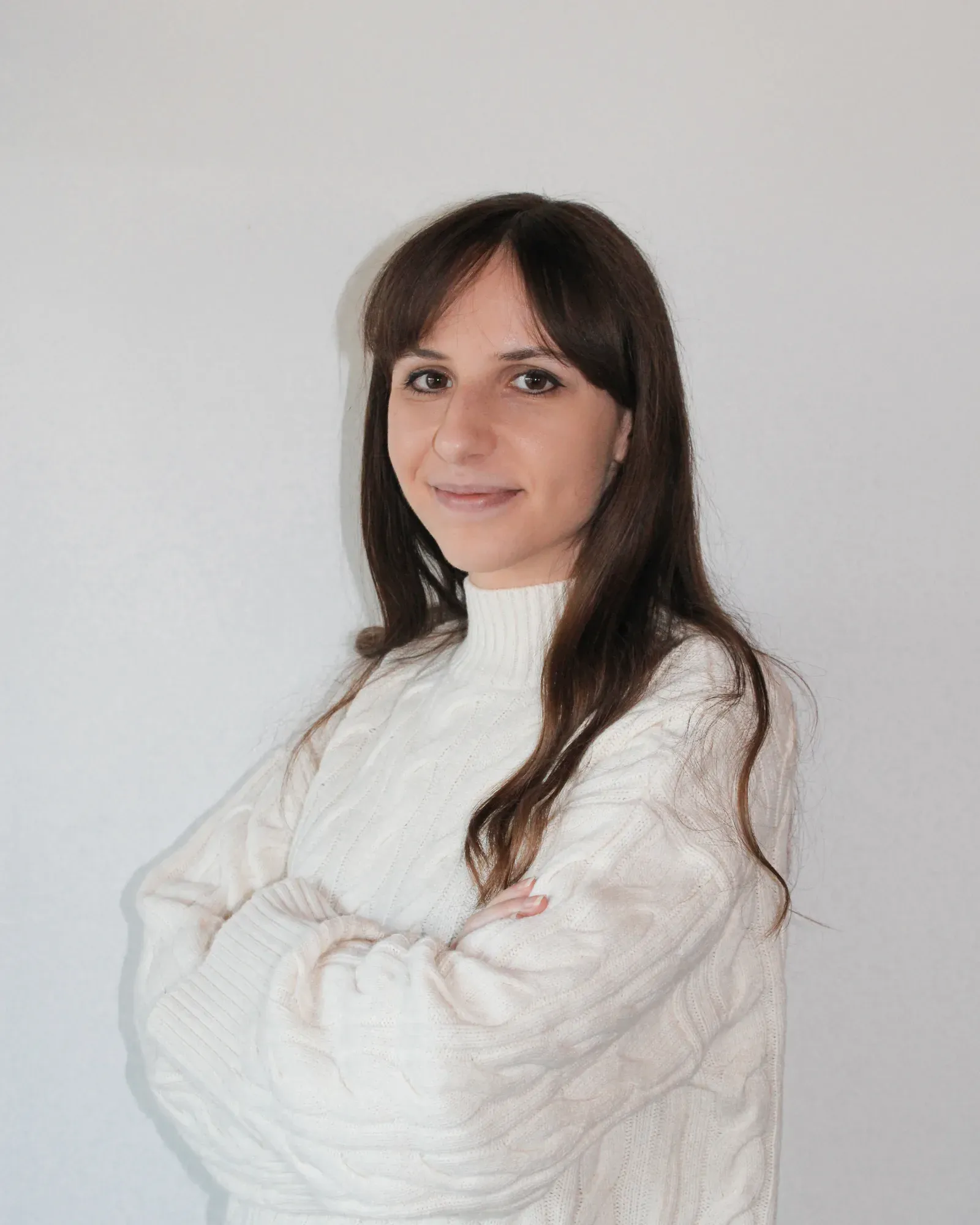 Jelena Janic, arms crossed, in a white knit sweater